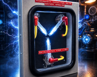 May include: A rectangular metal device with a black frame containing three glowing glass tubes arranged in a Y-shape, connected by yellow cables and red caps. Red labels read DISCONNECT CAPACITOR DRIVE BEFORE OPENING and SHIELD EYES FROM LIGHT.