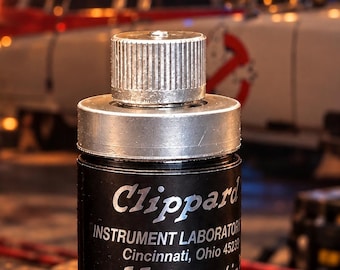Puede incluir: Un componente cilíndrico negro Clippard Instrument Laboratory Minimatic con una parte superior metálica plateada y una tapa estriada. La etiqueta presenta el texto: Clippard INSTRUMENT LABORATORY Cincinnati, Ohio 45239 Minimatic U.S. PAT. NO'S 3.766.935: 3.766.831.