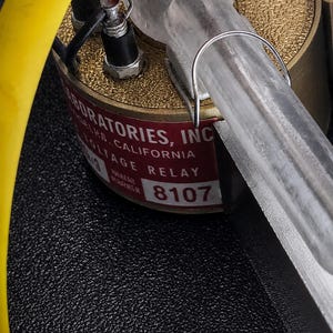 Close-up of a chrome relay base, red boot and yellow lead on one arm
