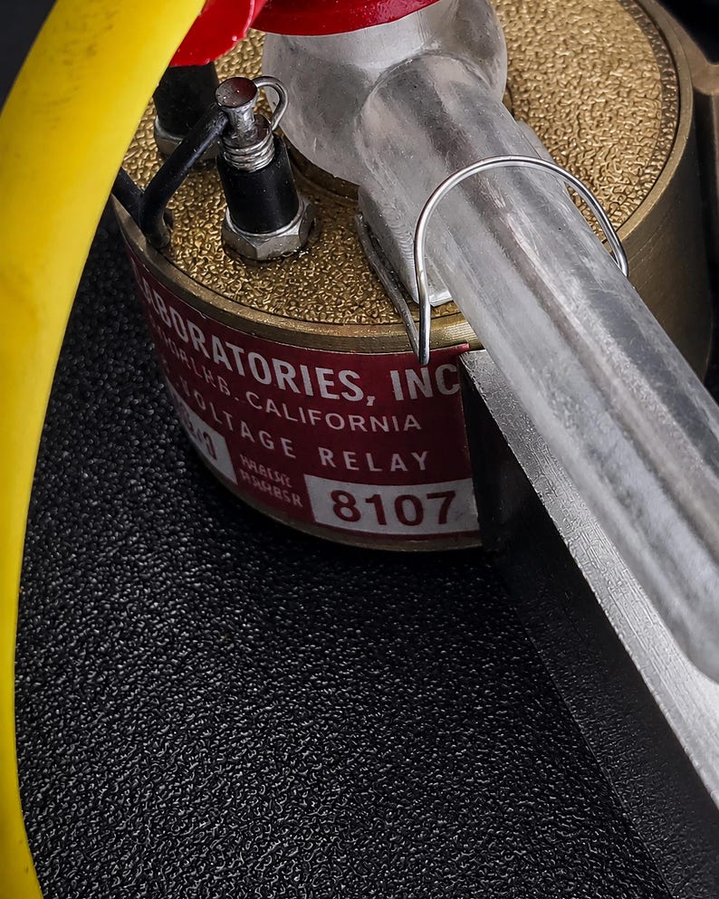 Close-up of a chrome relay base, red boot and yellow lead on one arm