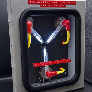 75% scale Flux Capacitor lit up, three glowing arms in a hinged metal case