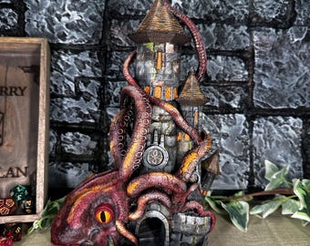 May include: A gray stone tower with a brown roof is wrapped in the tentacles of a red octopus. The octopus has a large, yellow eye. The tower has a small opening at the base, which is a dice rolling tray.