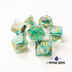 May include: A collection of seven multi-sided dice in various shapes. The dice are transparent with a teal and white marbled design, and gold numerals. The dice are scattered on a white surface. These dice are for tabletop games.