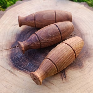 Könnte beinhalten: Drei Flaschenverschlüsse aus Holz in Fischform. Die Verschlüsse sind hellbraun und haben eine glatte, polierte Oberfläche.