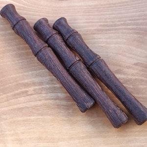 Könnte beinhalten: Drei Holzstift mit einer dunkelbraunen Beize. Die Stifte sind in Dreiecksform auf einer hellbraunen Holzoberfläche angeordnet.