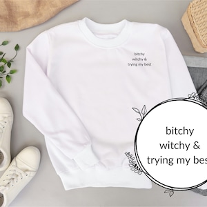 May include: White sweatshirt with the text "bitchy witchy & trying my best" printed on the front.