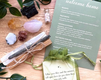 May include: A green pouch with a white card inside that reads "Follow your bliss and the universe will open doors for you where there were only walls. - Joseph Campbell". The pouch is surrounded by various crystals, a small bottle of salt, and two sticks of palo santo wood.