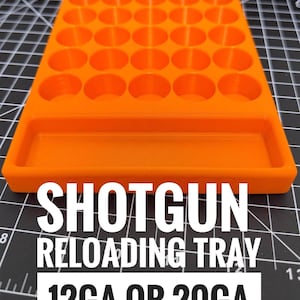 Pode incluir: Bandeja de recarga de espingarda laranja brilhante com vários compartimentos circulares e uma base retangular. O texto "SHOTGUN RELOADING TRAY 12GA OR 20GA" é exibido em letras brancas. A bandeja foi projetada para conter cartuchos de espingarda.