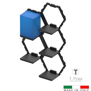 Puede incluir: Estantería de pared de metal negro con diseño geométrico. La estantería tiene múltiples plataformas cuadradas y un elemento azul en forma de cubo. El texto "T. Print" y "MADE IN ITALY" son visibles.