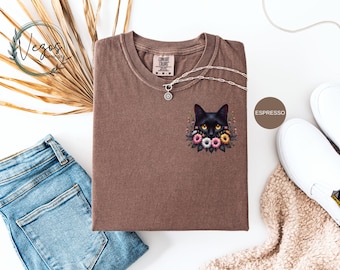 May include: A brown t-shirt with a black cat with yellow eyes surrounded by flowers. The text "ESPRESSO" is in the upper right corner of the image.