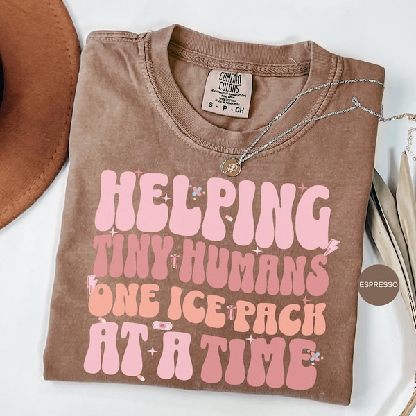 May include: A brown t-shirt with a pink and white graphic that says "Helping Tiny Humans One Ice Pack At A Time".