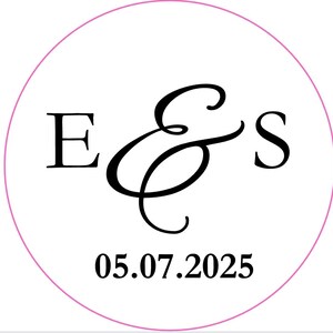May include: A white circular sticker with a pink border. The sticker features the letters "E & S" in black script, with the ampersand stylized. Below the letters is the date "05.07.2025" in a bold, sans-serif font. The design is simple and elegant.