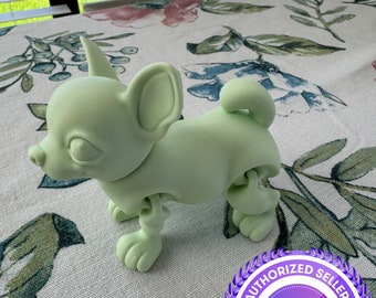 May include: A light green 3D printed articulated chihuahua figurine. The figurine is posed standing with its head tilted to the side. The figurine is on a white and green floral tablecloth. The image also includes a purple and white sticker with the text "Authorized Seller Printverse Authorized Seller".