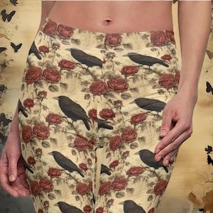May include: Black and white leggings with a floral pattern featuring red roses and black crows. The background is a cream color.