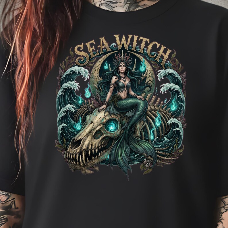May include: Black t-shirt featuring a detailed illustration of a mermaid with teal hair and a green tail, seated on a skull. The design includes ocean waves and the text "SEA WITCH" in gold lettering.