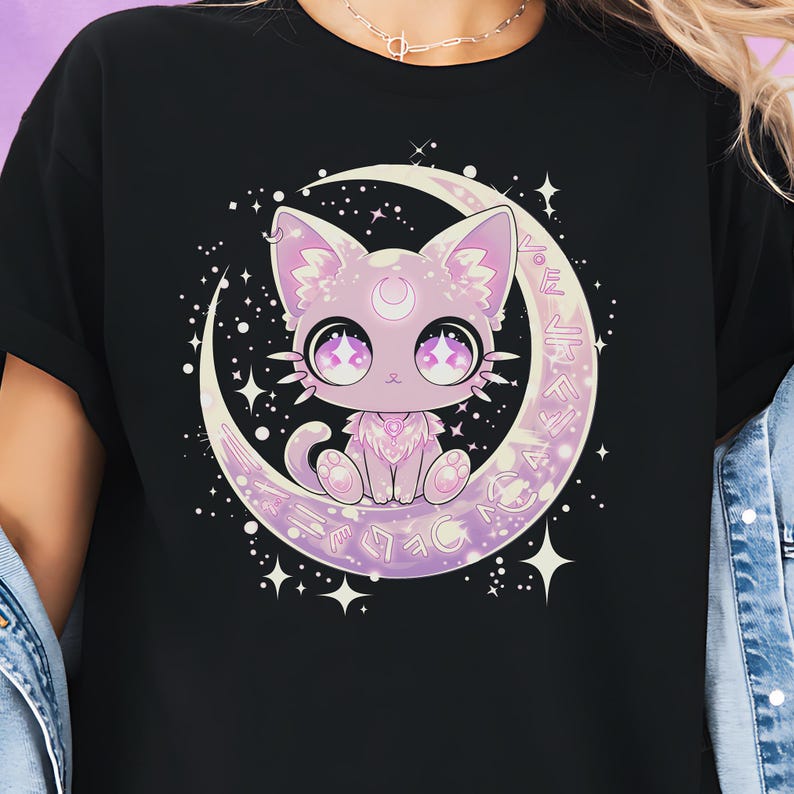 A kawaii pastel goth cat sits on a glowing crescent moon, surrounded by sparkling stars, runic symbols, and celestial details. The adorable purple cat has big anime-style eyes, a crescent moon on its forehead, and a magical girl aesthetic, making this tee perfect for alt girls, Harajuku lovers, EGirl fashion fans, and anyone who loves witchy, mystical, and cute celestial cat designs.