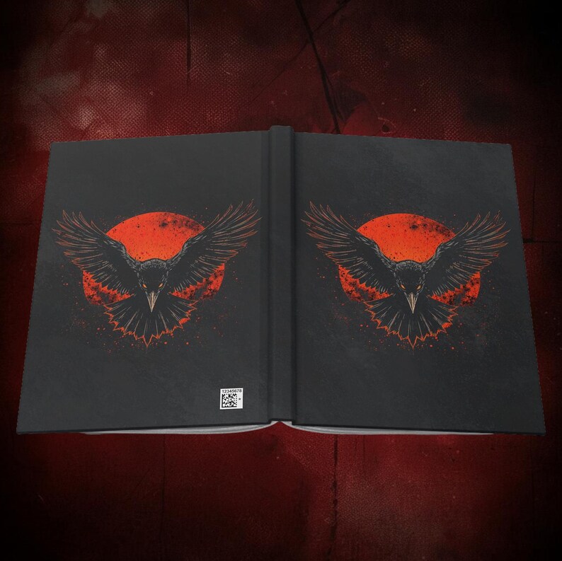 May include: A black journal with a raven design. The raven is depicted with outstretched wings against a red sun. The journal is open, displaying the design on both sides. The background is a dark red.