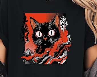 May include: Black t-shirt featuring a graphic of a black cat with large white eyes, set against a red background. The design includes stylized red and white smoke-like elements and Japanese text. The cat's face is the focal point.