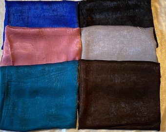 May include: Five silk scarves in different colors: blue, pink, gray, teal, and brown. The scarves are arranged in a row on a white surface.