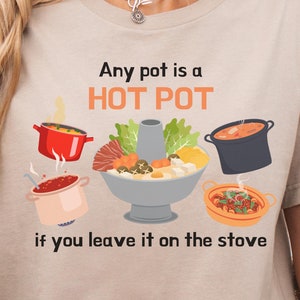 May include: Tan t-shirt with a humorous saying about hot pots. The text reads "Any pot is a HOT POT if you leave it on the stove". The graphic features a variety of pots with steaming food.