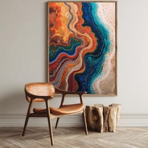 Puede incluir: Impresión artística abstracta con marco de madera. La obra presenta un diseño colorido y fluido con tonos de naranja, azul, verde y marrón. Una silla de madera con asiento de cuero y una mesa auxiliar de madera están en primer plano.