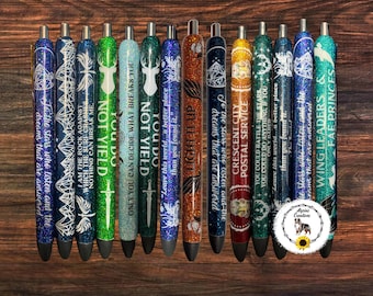 May include: A collection of fourteen glittery pens arranged in a row, each featuring unique colors and printed text including phrases like To the stars who listen, Light it up, and Wing leaders and fae princes, with a small circular logo included.