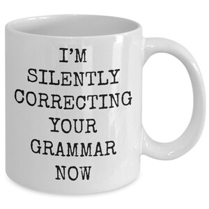 Peut inclure: Une tasse à café en céramique blanche avec du texte noir qui dit "Je corrige silencieusement votre grammaire maintenant".