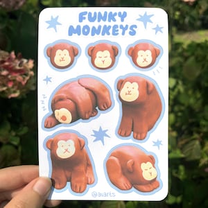 May include: A sticker sheet featuring the text "FUNKY MONKEYS" in blue, with illustrations of brown monkeys with cream-colored faces. The monkeys are in various poses, including sleeping and sitting. Blue star accents are also included.