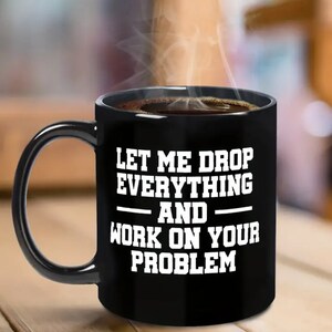 May include: Black coffee mug with white text that reads "Let me drop everything and work on your problem".