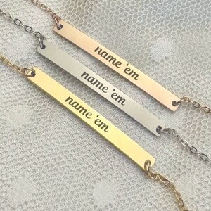 May include: Three gold, silver, and rose gold bar necklaces with the text "name 'em" engraved on each.