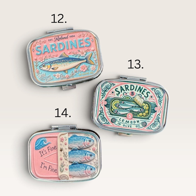 May include: Three rectangular metal tins with hinged lids, labeled 12, 13, and 14. Tin 12 features a pink sardine illustration. Tin 13 shows sardines with lemon slices and ornate green scrollwork. Tin 14 is pink with three fish and the text It's Fine I'm Fine.
