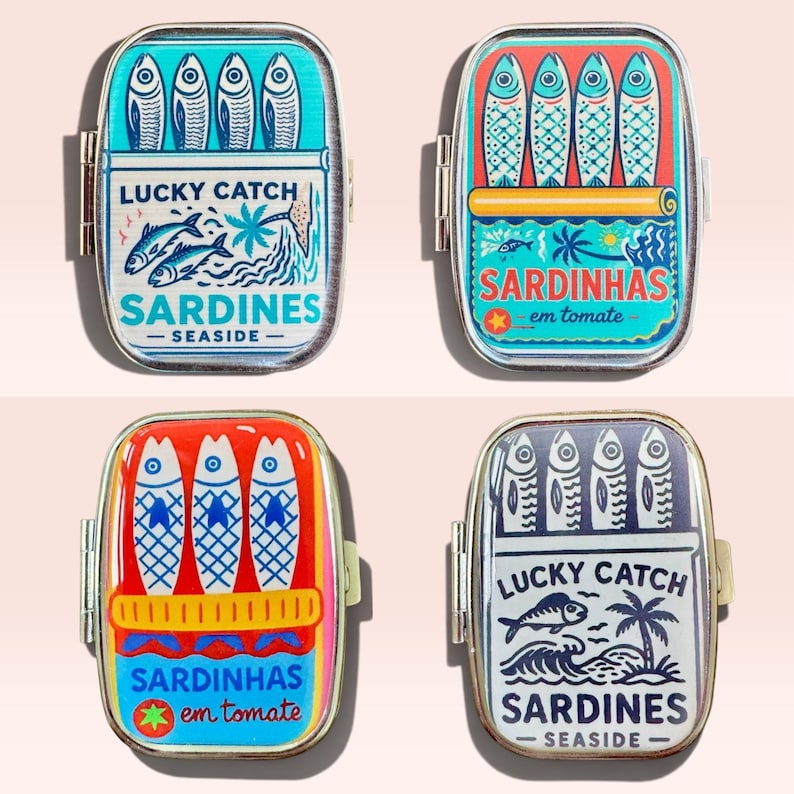 May include: Four rectangular metal tins featuring colorful graphic illustrations of sardines. Two tins display the text Lucky Catch Sardines Seaside, while the other two feature the text Sardinhas em tomate with stylized fish and palm tree motifs.