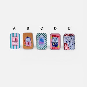 May include: Five rectangular metal tins labeled A through E, each featuring unique sardine-themed illustrations. Designs include blue stripes, orange with fish, green checkerboard, pink with lemon slices, and a dense pattern of blue fish with red text.