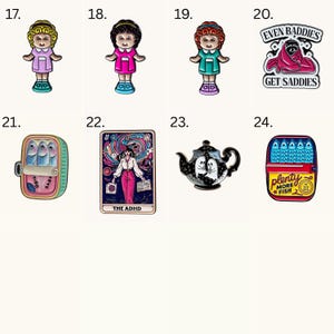 May include: A collection of eight enamel pins featuring various designs including three distinct dolls with different hair and clothing colors, a raccoon in a blanket with the text EVEN BADDIES GET SADDIES, a sardine tin, a tarot card labeled THE ADHD, a teapot with ghosts, and a sardine tin with the text plenty MORE FISH IN THE SEA.