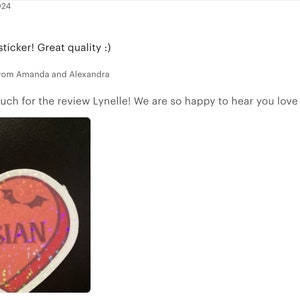 May include: A red heart-shaped sticker with glitter and a white outline. The sticker has a pair of bat wings and the word "CASSIAN" printed in white letters.