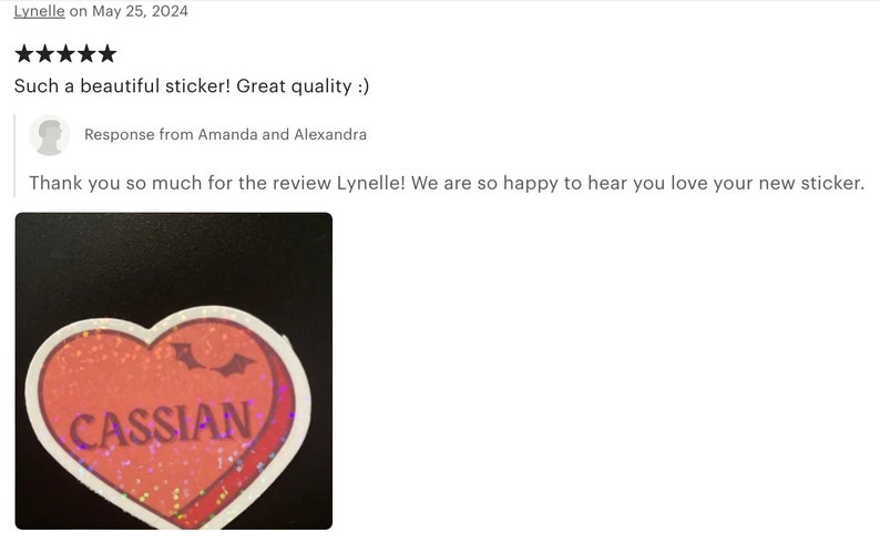 May include: A red heart-shaped sticker with glitter and a white outline. The sticker has a pair of bat wings and the word "CASSIAN" printed in white letters.