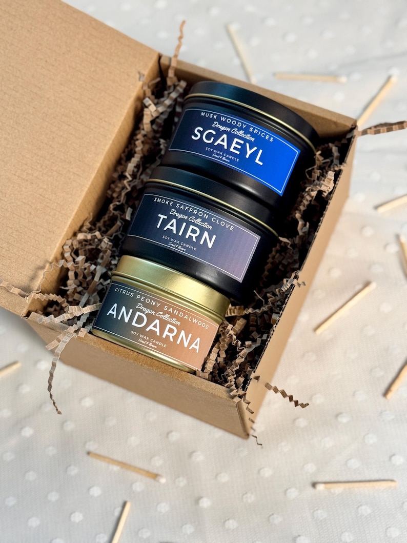 Puede incluir: Una caja de regalo llena de tres velas de cera de soja. Las velas est&aacute;n en latas de metal con tapas doradas. Las velas est&aacute;n etiquetadas con los nombres "Sgaeyl", "Tairn" y "Andarna". Cada vela tiene un aroma diferente y forma parte de la "Colecci&oacute;n Drag&oacute;n".
