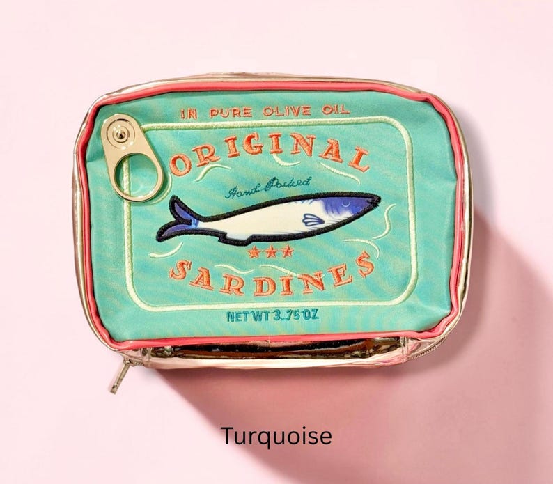 May include: A rectangular turquoise zippered pouch designed to resemble a tin of sardines. The front features embroidered text reading ORIGINAL SARDINES, IN PURE OLIVE OIL, HAND PACKED, and NET WT 3.75 OZ, with a fish graphic and a metal pull tab.