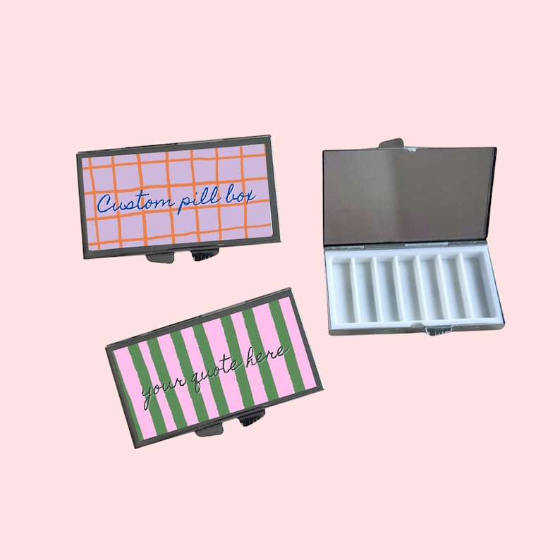Op de afbeelding: Drie rechthoekige pillendoosjes met zilveren metalen frames. Twee doosjes hebben kleurrijke deksels met tekst: een met een roze raster en "Custom pill box", de andere met groene en roze strepen en "your quote here". Het derde doosje is open en onthult witte compartimenten.
