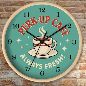 May include: A round wall clock with a light wood frame. The clock face is teal with a coffee cup illustration and the words "PERK-UP CAFE" and "ALWAYS FRESH!". Black hands indicate the time. The clock is against a brick wall.