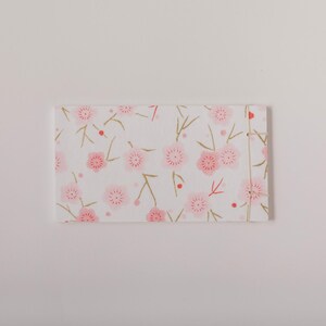 May include: A rectangular notebook with a white background and a repeating pattern of pink cherry blossoms and gold stems. The notebook is bound with a natural-colored thread.
