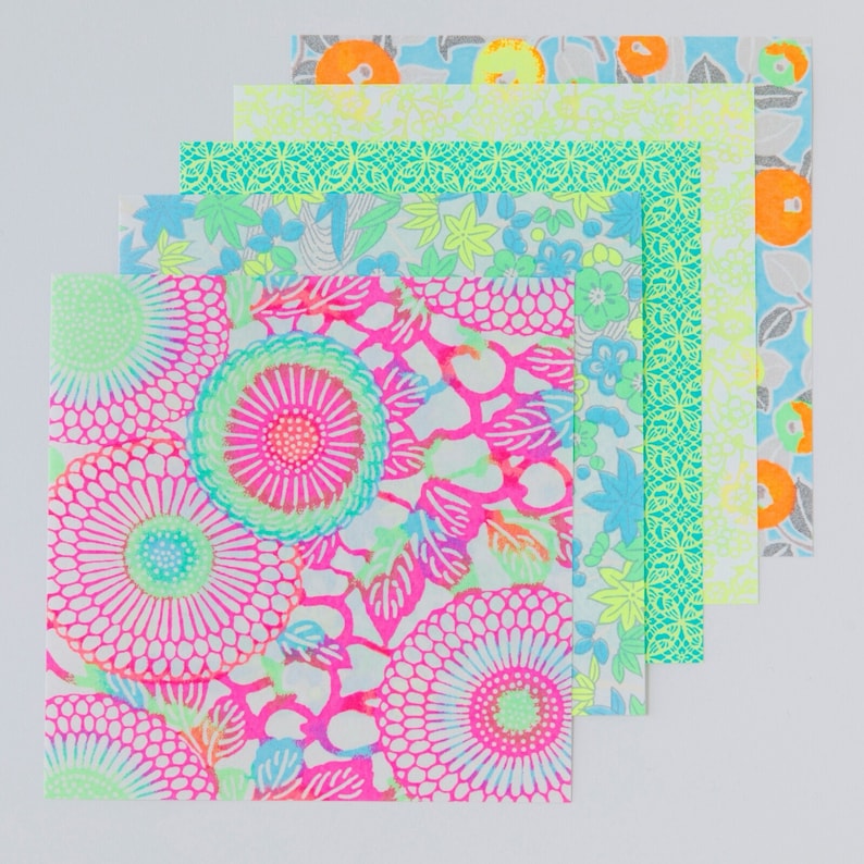 May include: A set of five colorful patterned origami paper sheets. The sheets feature a variety of floral and geometric designs in shades of pink, blue, green, and yellow.