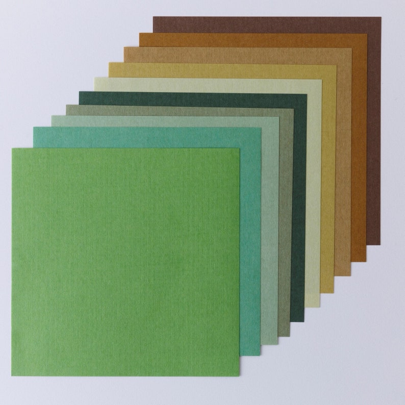 Pode incluir: Um conjunto de 12 quadrados de papel de diferentes cores, que v&atilde;o do castanho ao verde. Os quadrados est&atilde;o dispostos em forma de leque, com o quadrado maior na parte inferior e o menor na parte superior.