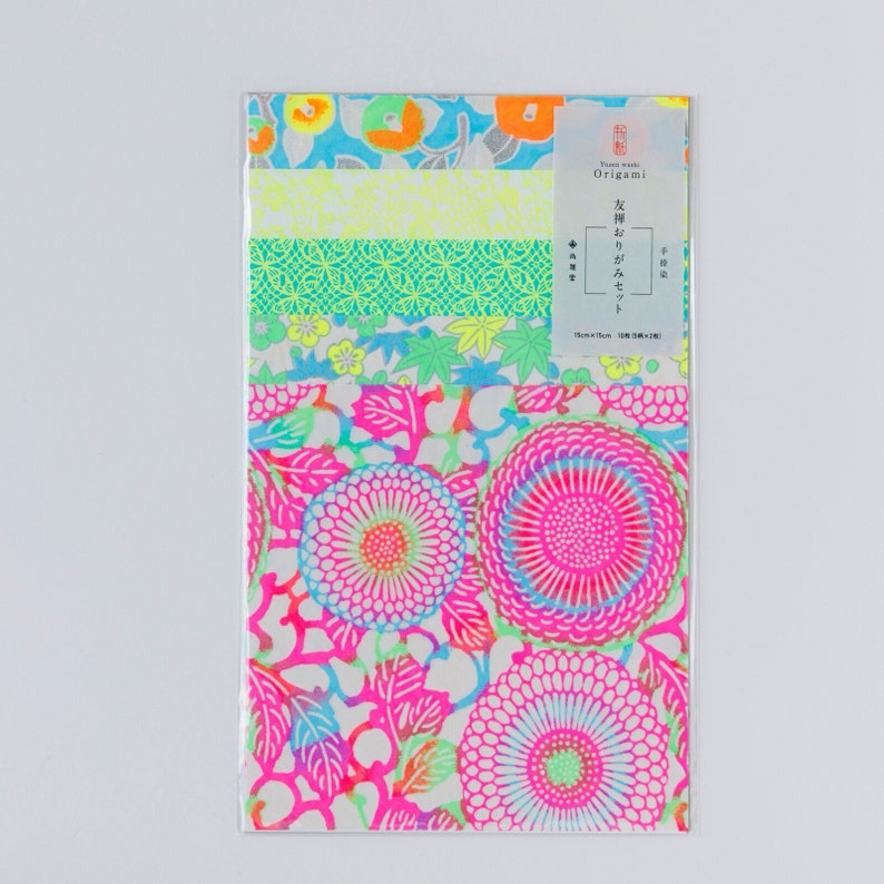 May include: A pack of colorful origami paper with a variety of patterns, including flowers, geometric designs, and a blue and white pattern. The pack is labeled "Yume Washi Origami" and "光輝りかがやきセット".