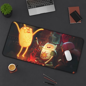 May include: A rectangular desk mat featuring a vibrant, dark-toned illustration of two cartoon characters from Adventure Time. One character is a glowing yellow dog-like figure, and the other is a human-like figure with a sword and sun emblem.