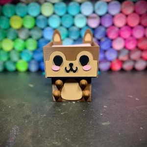 Könnte beinhalten: Eine braune und beige Holzbox in Form eines Cartoon-Chipmunks. Das Chipmunk hat schwarze Augen, rosa Wangen und eine kleine schwarze Nase. Die Box ist rechteckig mit dem Gesicht des Chipmunks auf der Vorderseite.