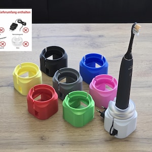 May include: A collection of seven cylindrical toothbrush charging stands in yellow, black, grey, blue, pink, green, and white. The white stand holds a black electric toothbrush. An inset graphic shows items not included with the red X symbol.