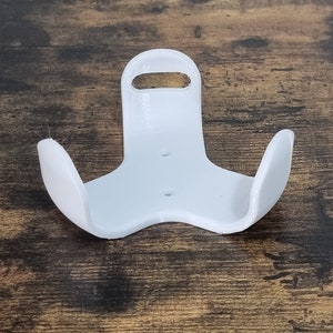 Peut inclure: Support mural en plastique blanc avec un design incurvé, adapté pour tenir un petit objet.