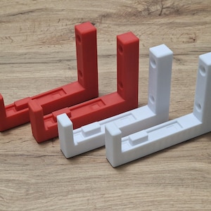 Puede incluir: Dos juegos de soportes de estantería de pared. Un juego es rojo y el otro es blanco.