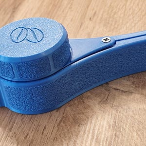 May include: A blue plastic coffee bean grinder with a textured surface and a screw on the side.